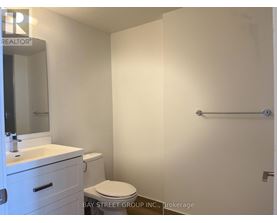 A white bathroom with a toilet, sink, and mirror.