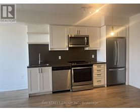 A modern kitchen with a stainless steel refrigerator and oven.