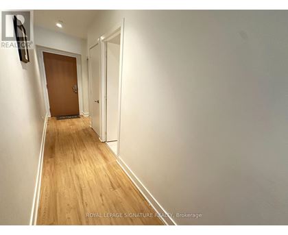 A hallway with a wooden floor and white walls.
