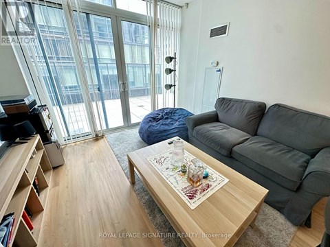 A living room with a grey couch, a coffee table with a map on it, and a large window with a view of a building outside.