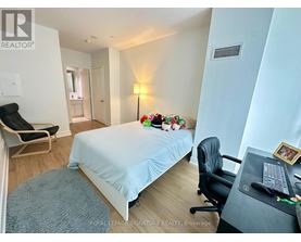A bedroom with a bed, desk, chair, and a lamp.