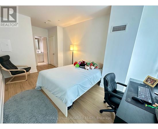 A bedroom with a bed, desk, chair, and a lamp.