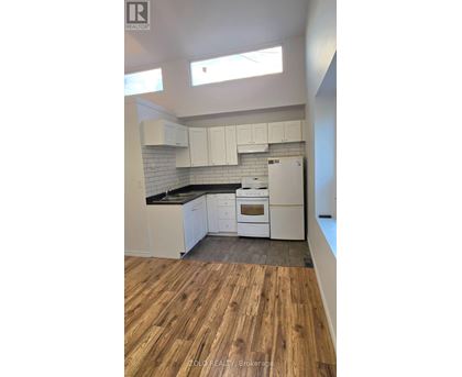 A kitchen with white cabinets and a wooden floor.