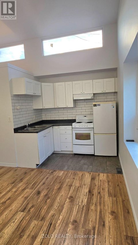 A kitchen with white cabinets and a wooden floor.