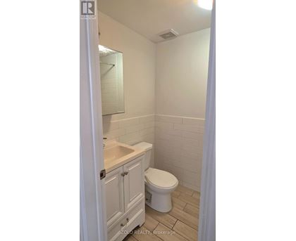 A white toilet in a small bathroom with a sink and a mirror.