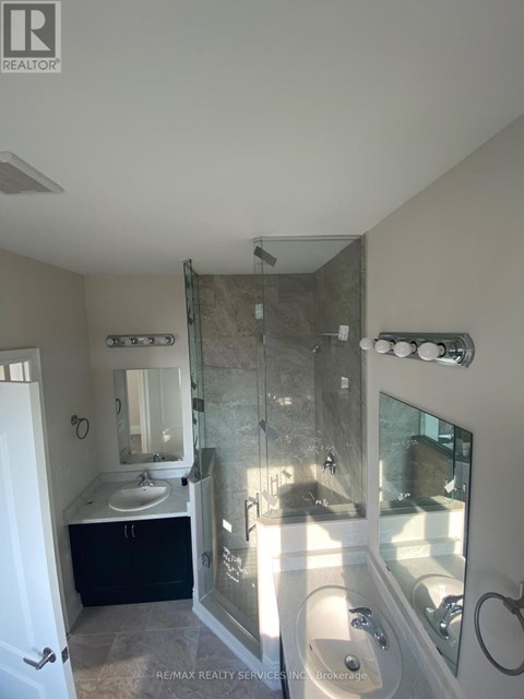 A bathroom with a walk in shower and a sink.
