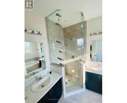 A bathroom with a glass shower door and a marble countertop.