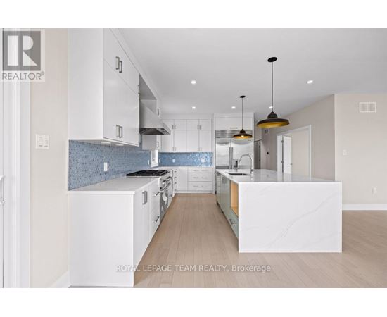 A modern kitchen with white cabinets and a marble island.