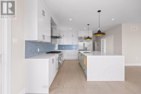 A modern kitchen with white cabinets and a marble island.