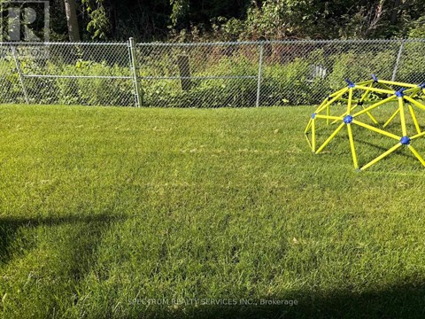 A yellow geometric structure sits on a grassy field.