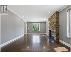 A spacious room with a stone fireplace and wooden floors.
