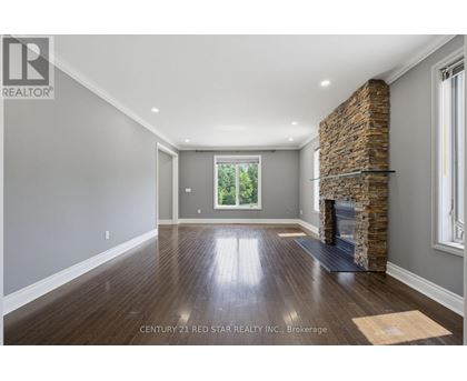 A spacious room with a stone fireplace and wooden floors.