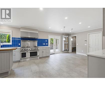 A spacious kitchen with a stove top oven and a blue backsplash.