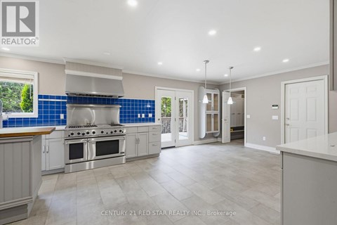 A spacious kitchen with a stove top oven and a blue backsplash.