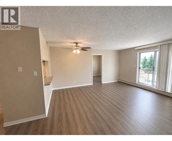 A spacious room with a ceiling fan and sliding glass doors.