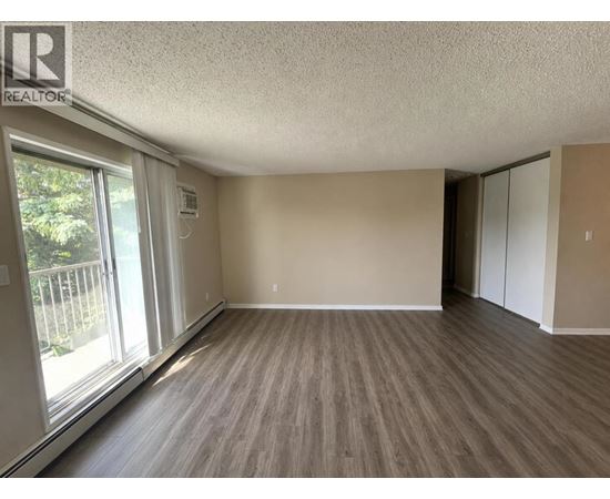 A room with wooden flooring and a sliding glass door.