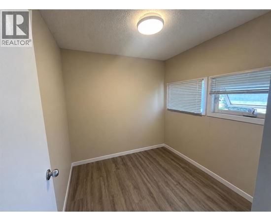 A room with a door, window, and wooden flooring.