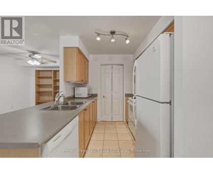A kitchen with a sink, refrigerator, and cabinets.