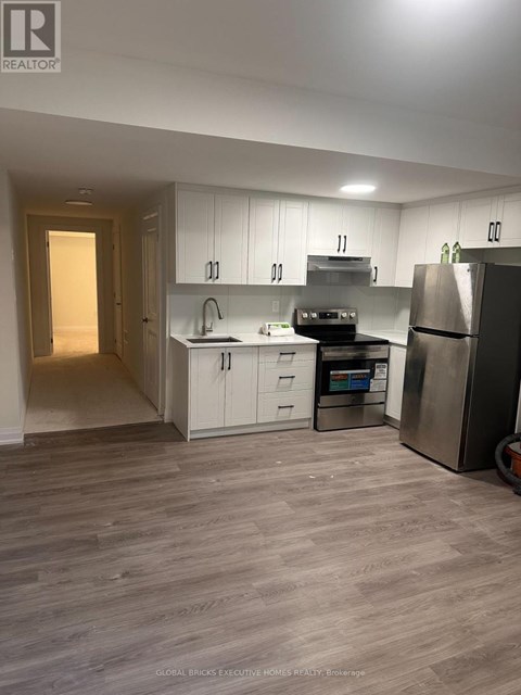A kitchen with white cabinets and a refrigerator.