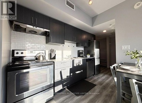 A modern kitchen with a stove top oven and a refrigerator.