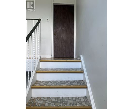 A brown door is at the end of a staircase with a white railing.