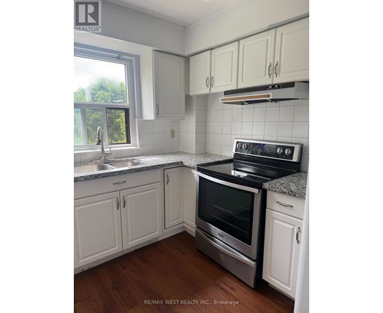 A kitchen with white cabinets and a stove top oven.