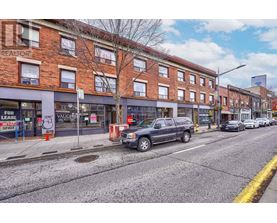 A street view with a building on the left and a car parked on the sidewalk.