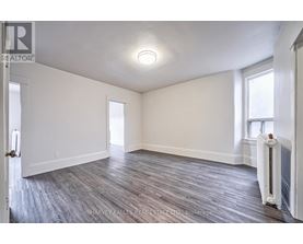 A spacious room with wood flooring and white walls.