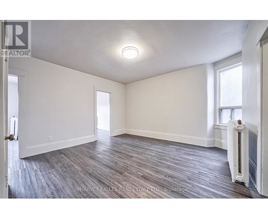 A spacious room with wood flooring and white walls.