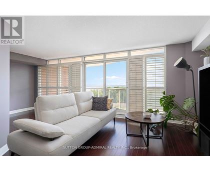 A living room with a white sofa and a table with a plant on it.