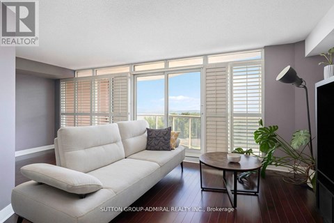 A living room with a white sofa and a table with a plant on it.