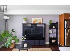 A living room with a flat screen TV and a plant on the side.