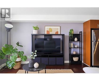 A living room with a flat screen TV and a plant on the side.