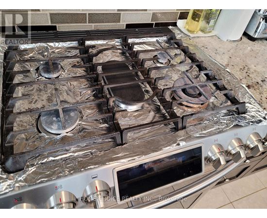 A stove top with four burners and a pot on the second one from the left.