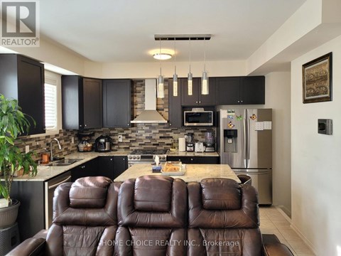 A brown leather couch is in the middle of a modern kitchen.