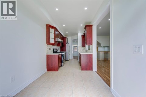 A spacious kitchen with red cabinets and a white floor.