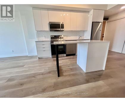 A kitchen with white cabinets and a black island.