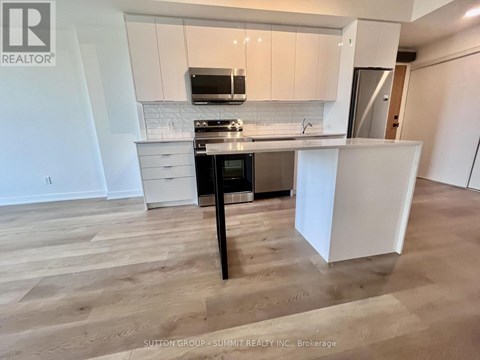 A kitchen with white cabinets and a black island.