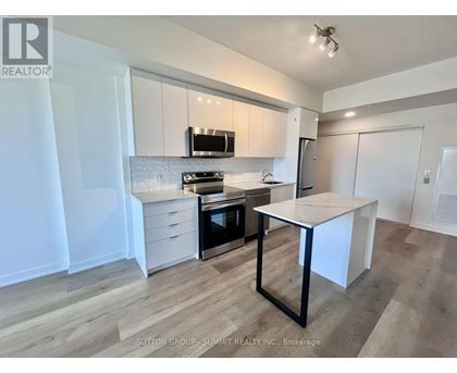 A kitchen with white cabinets and a black and white island.
