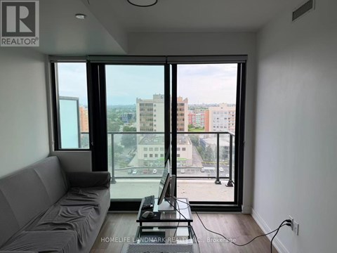 A living room with a grey sofa and a table with a laptop on it.