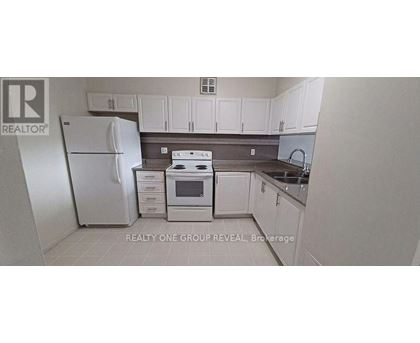 A white refrigerator is in a kitchen with white cabinets.
