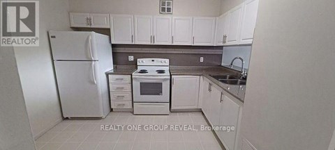 A white refrigerator is in a kitchen with white cabinets.