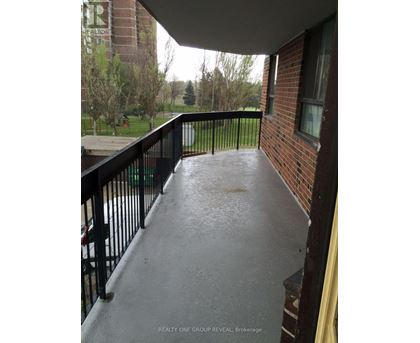 A balcony with a black railing and a view of a grassy area.