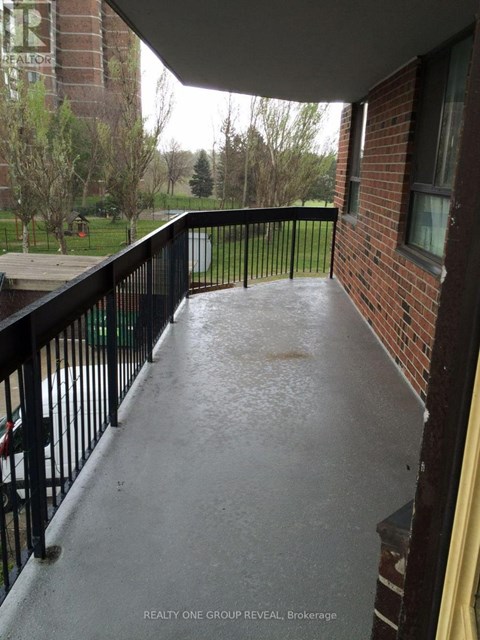 A balcony with a black railing and a view of a grassy area.