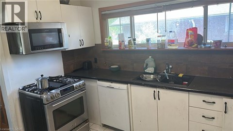 A kitchen with a stove, oven, microwave, and cabinets.