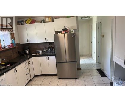 A kitchen with a refrigerator, cabinets, and a counter.