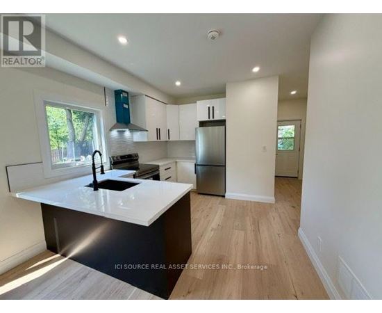 A modern kitchen with white countertops and wooden flooring.