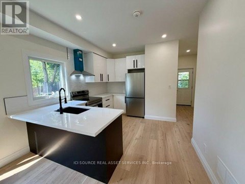 A modern kitchen with white countertops and wooden flooring.