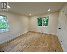 A room with wooden flooring and a window with a view of trees.