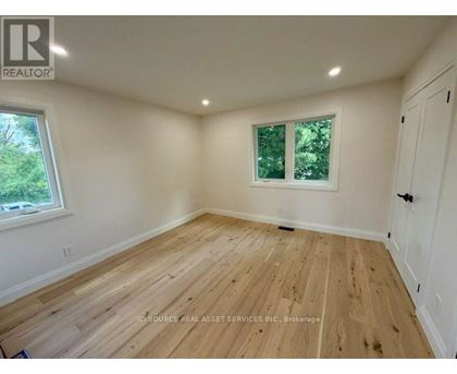 A room with wooden flooring and a window with a view of trees.